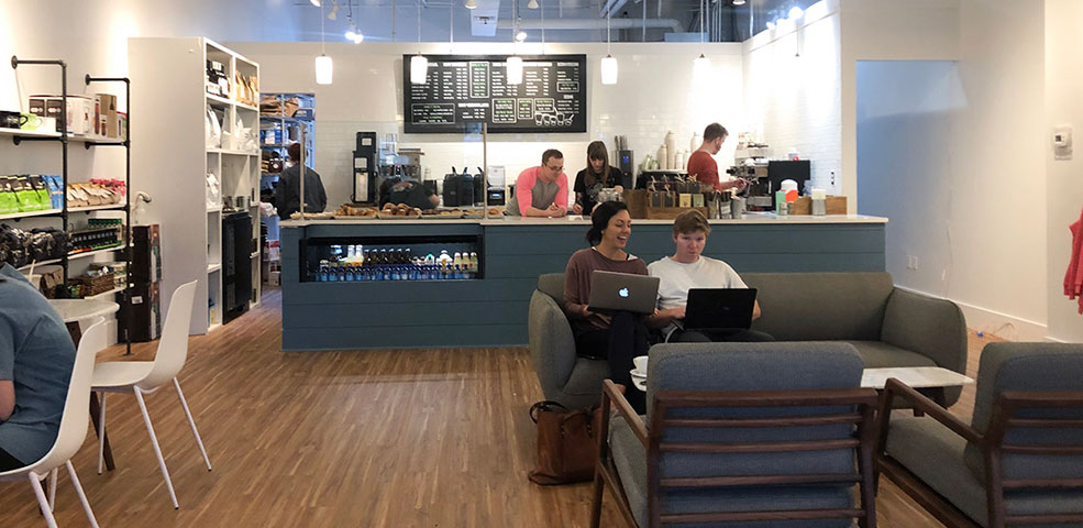 The "after" view of Amavida's Rosemary Beach, FL dream cafe design in 2019. See people sitting on couches enjoying bright cafe atmosphere.